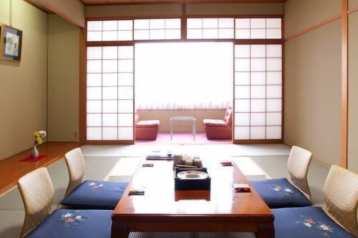 Una habitación japonesa tradicional con suelo de tatami, una mesa baja de madera y paneles shoji.