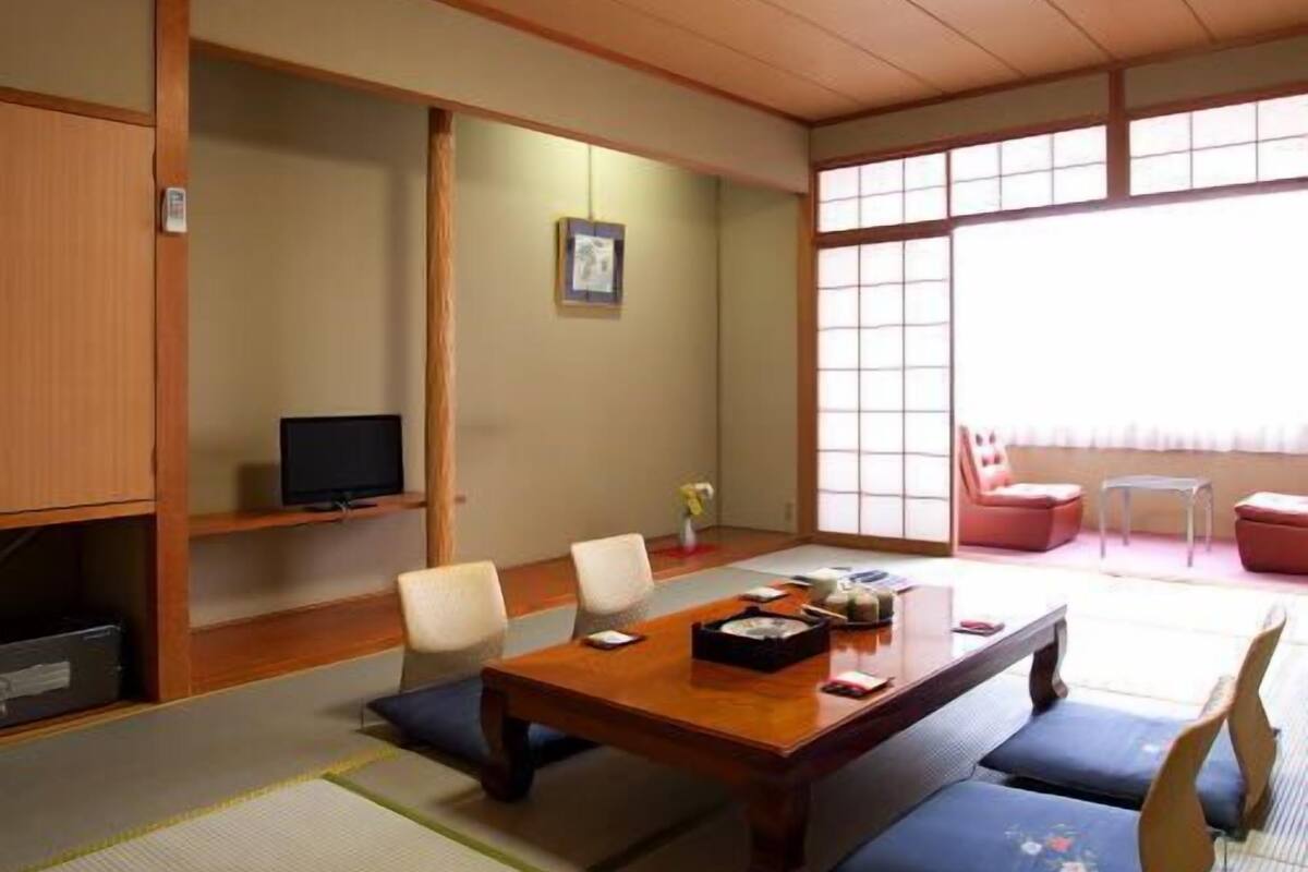 Una habitación japonesa tradicional con suelo de tatami, una mesa baja y puertas correderas.