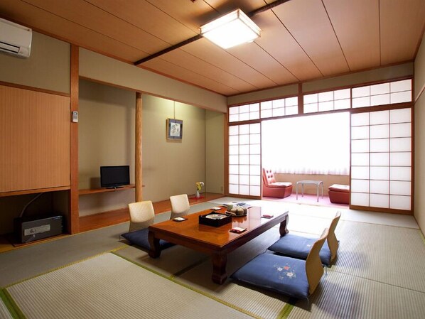 A traditional Japanese room with tatami flooring, a low table with cushions, a television, and sliding doors. - Ashihara Onsen Hakuwaso (Awara)