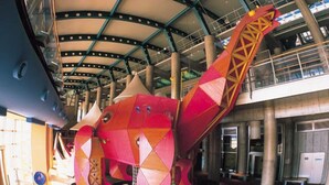 A large, colorful, geometric sculpture in an indoor space with a high ceiling and industrial elements. - Ashihara Onsen Hakuwaso (Awara)