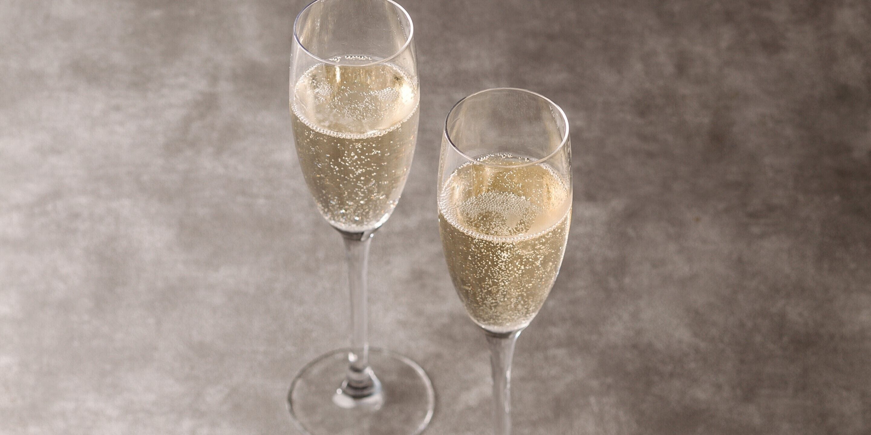 Two champagne glasses on a textured surface.