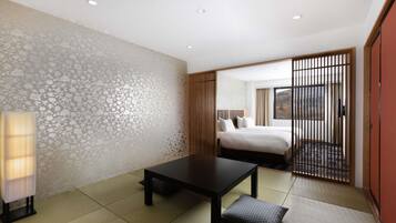 A hotel room with tatami flooring, a bed with a view, a table, and a traditional sliding door.