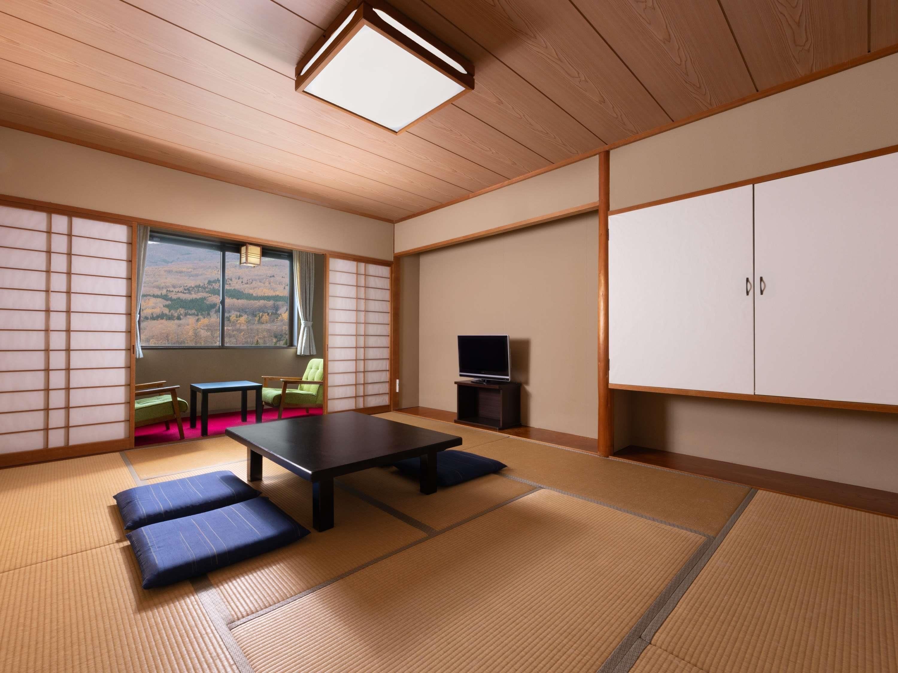 Una habitación japonesa tradicional con suelo de tatami, una mesa baja, una silla verde, un televisor y un armario.