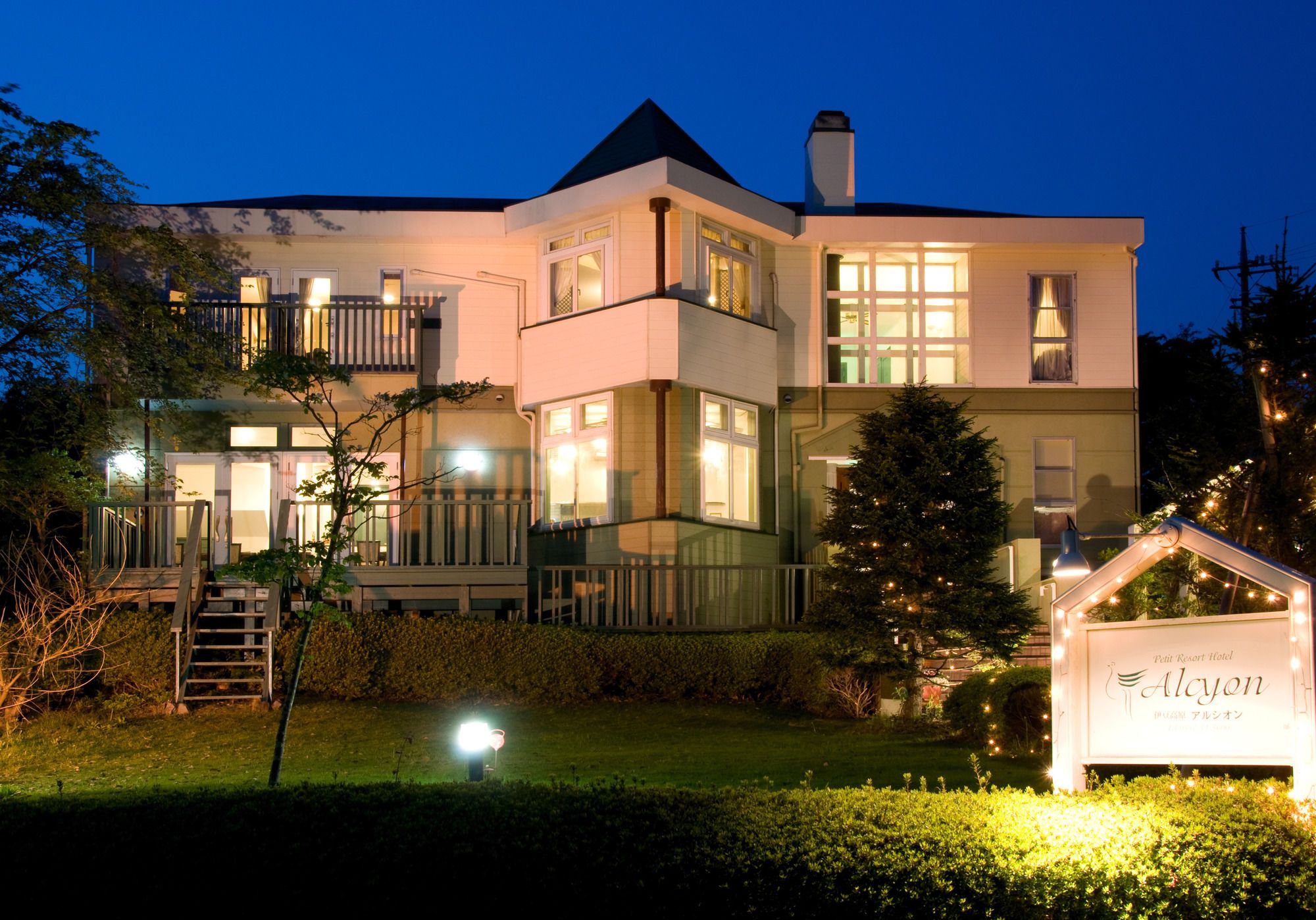 A two-story building with multiple windows, a balcony, and a sign indicating it is a hotel.