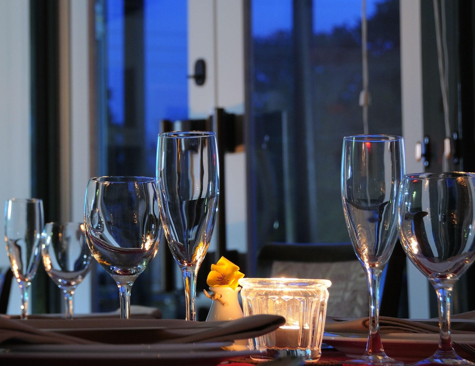 A table set with multiple wine glasses and a candle, with a window in the background.