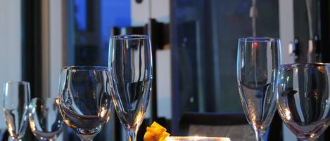 A table set with multiple wine glasses and a candle, with a window in the background.