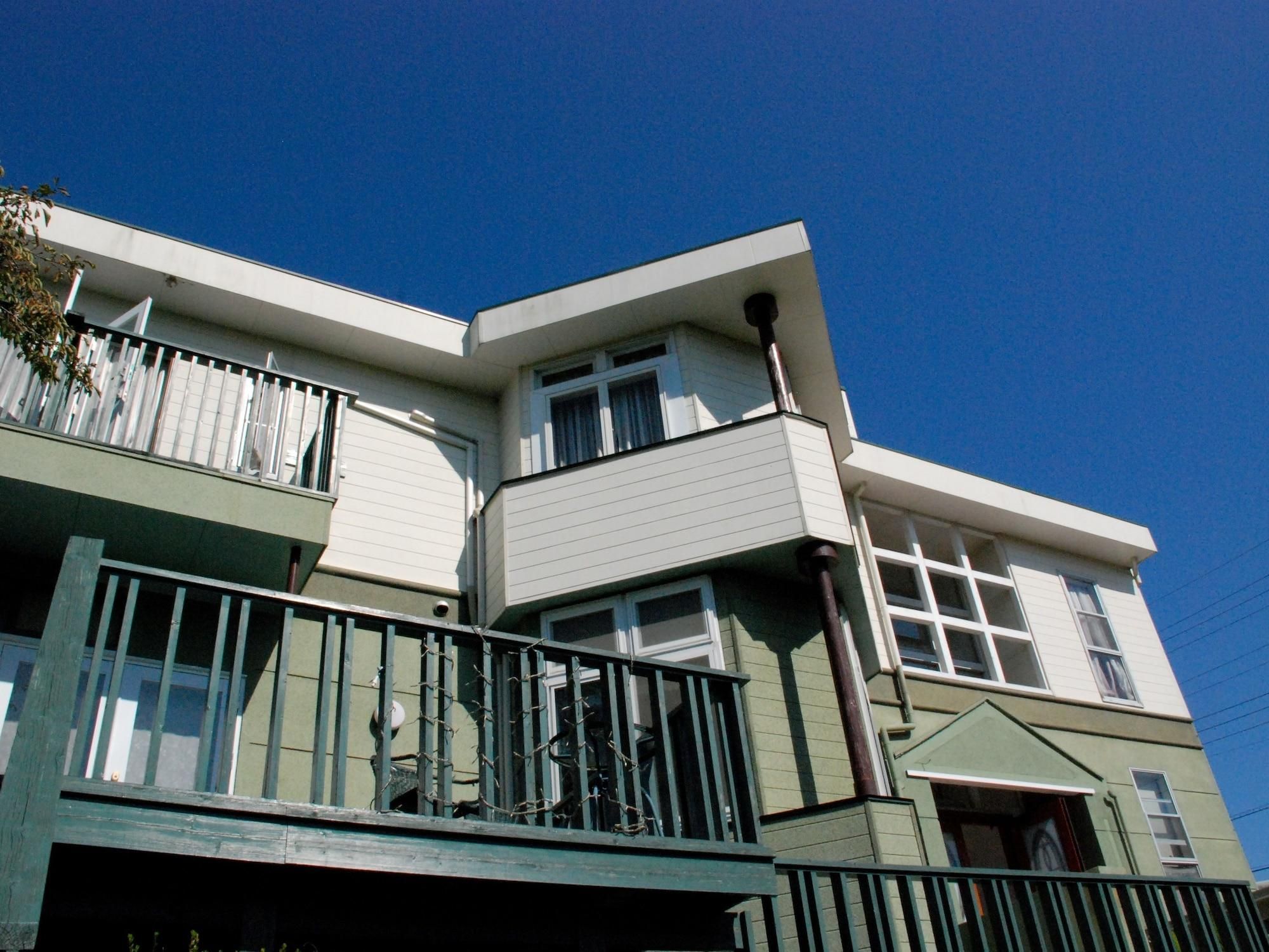A two-story building with a balcony on the ground floor and a garage entrance.