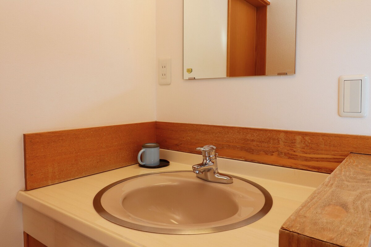 A bathroom with a sink, mirror, and a cup.