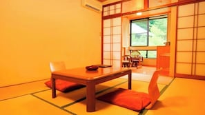 Une pièce de style japonais traditionnel, avec un sol recouvert de tatamis, une table basse et une porte coulissante donnant sur un jardin.
