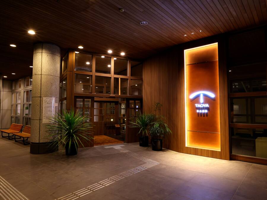 A hotel lobby with a wooden ceiling, a reception desk, and a sign for 'TAOYA'.