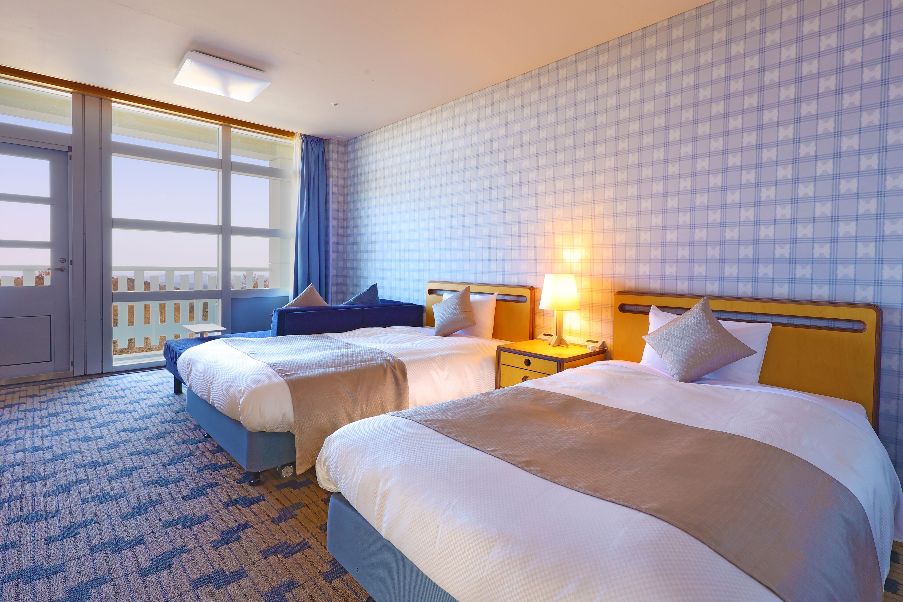 Una camera d'albergo con due letti, un'ampia finestra vista, una moquette decorata e un poggiatesta in legno.