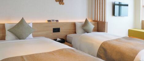 A hotel room with two beds, a wooden headboard, a mounted TV, and a wall-mounted light fixture.