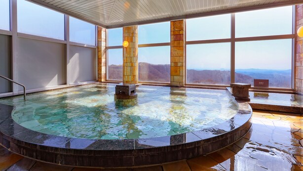Een hottub met uitzicht op de bergen, grote ramen en een houten plafond.