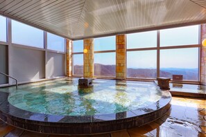 Un jacuzzi con vistas a las montañas, ventanas amplias y techo de madera.