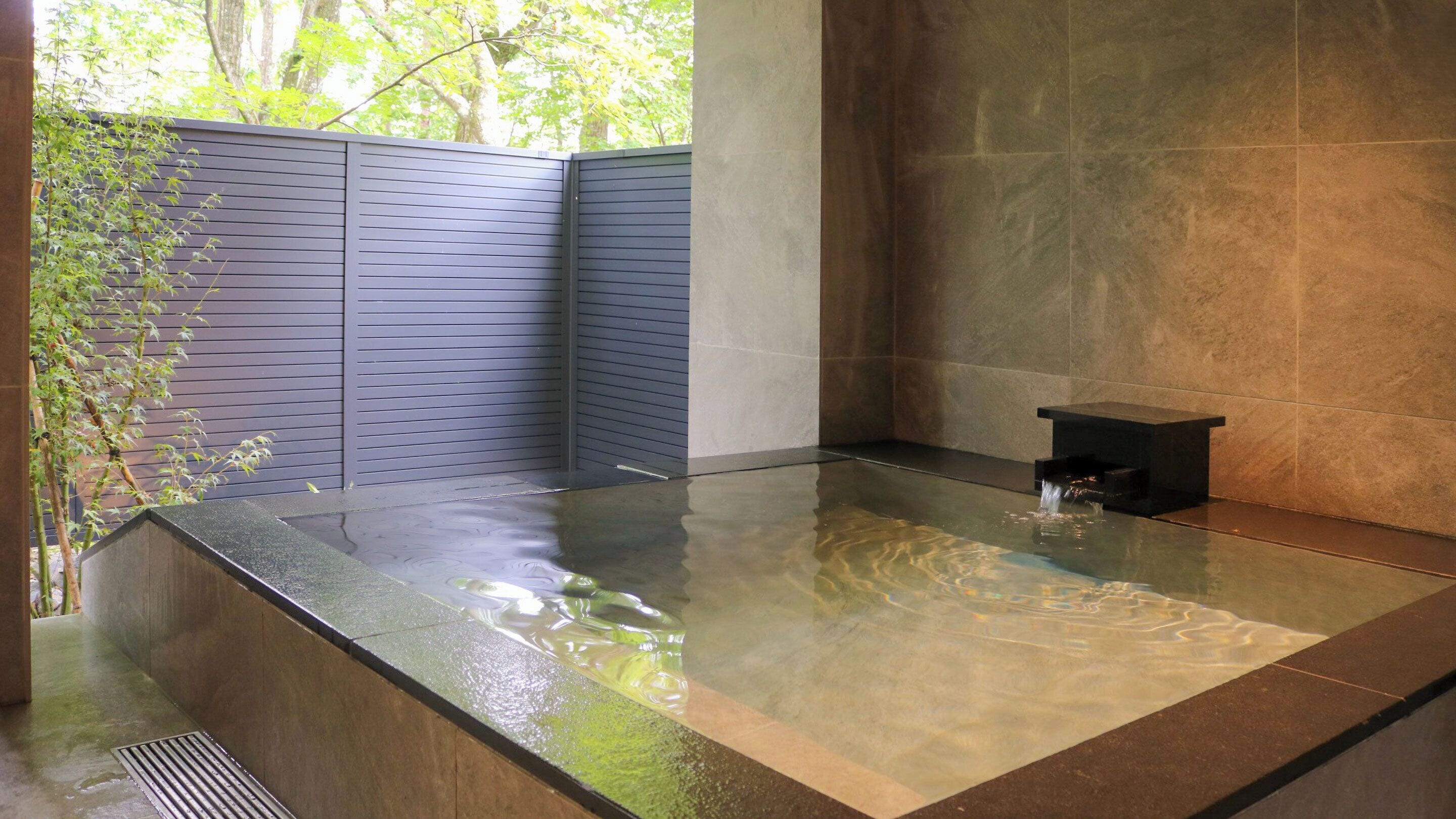 A modern spa area with a rectangular hot tub, a small black bench, and a wall with a vertical garden.