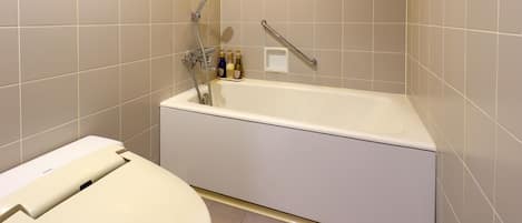 Un baño con bañera, inodoro y barras de apoyo.