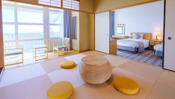 A hotel room with tatami flooring, a bed, a bedside table, a lamp, a chair, and a view through a sliding door.