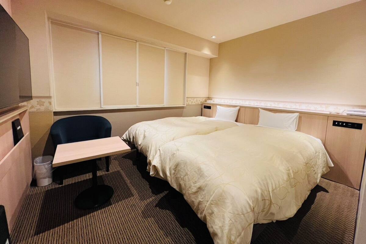 A hotel room with a bed, a desk, a chair, and a window.