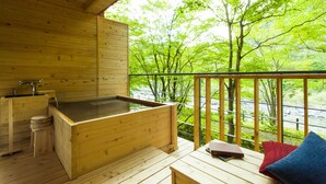 Una cabaña de madera con hidromasaje, una mesa con libros y almohadas.