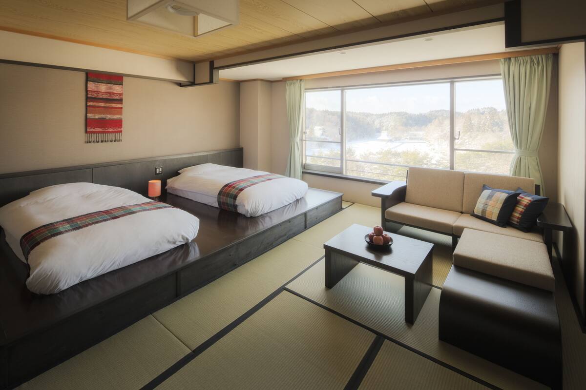 A hotel room with two beds, a sofa, a coffee table, and a view of a lake.