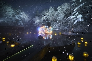 A serene winter scene with snow-covered trees and a reflective water surface.