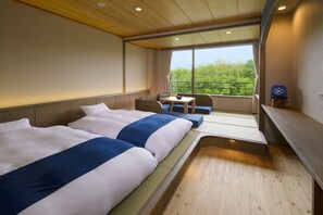 Une chambre d’hôtel avec deux lits, une petite table et une vue sur la verdure par la fenêtre.