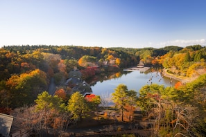A scenic view of a lake surrounded by autumn-colored trees and traditional buildings.
