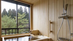 A wooden cabin with a wooden bathtub, a shower, and a window overlooking a forest. - Hoshino Resorts Aomoriya (Rokunohe)