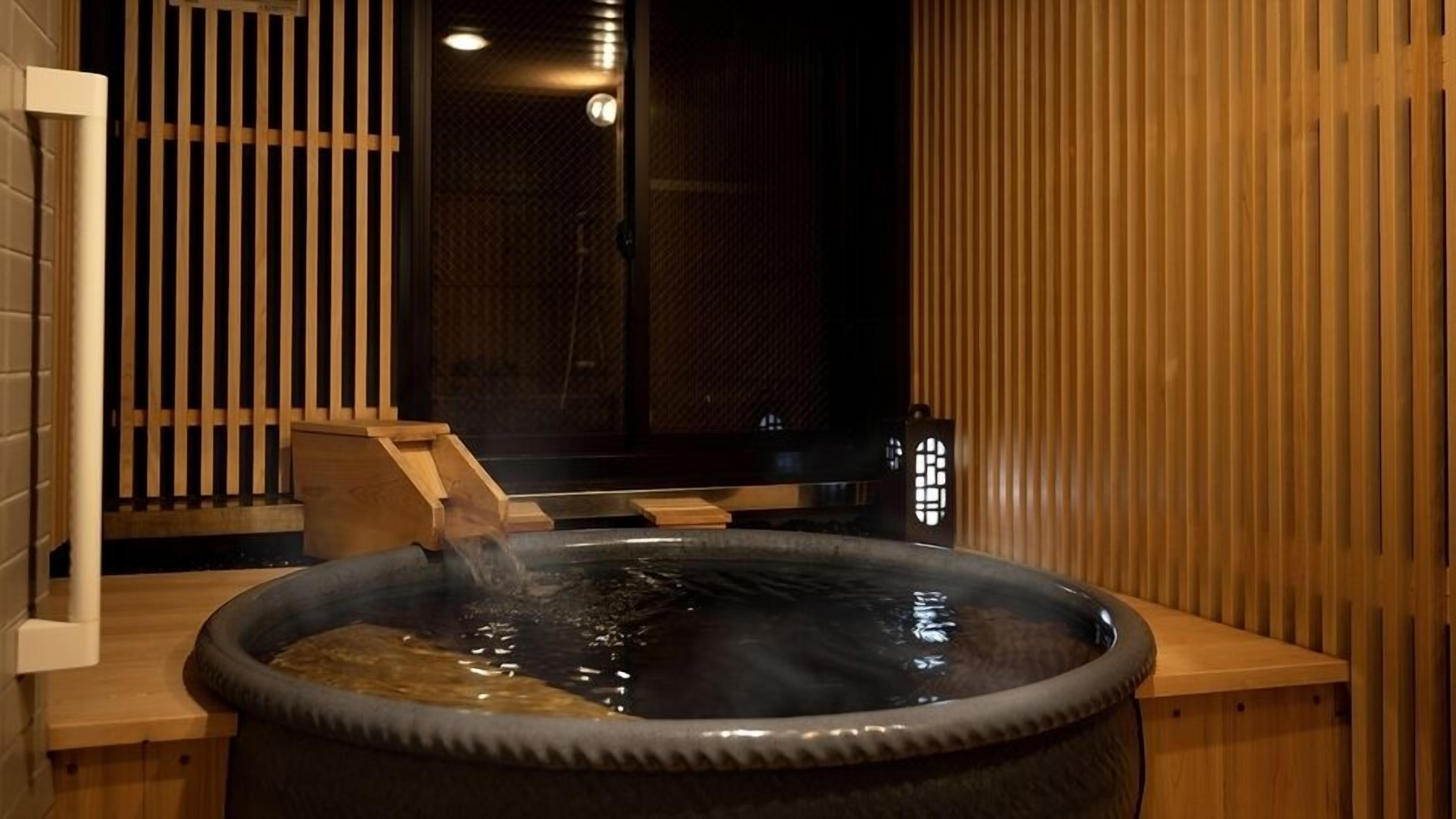 A hot tub with a wooden bench, a wooden partition, and a small table with a lamp.