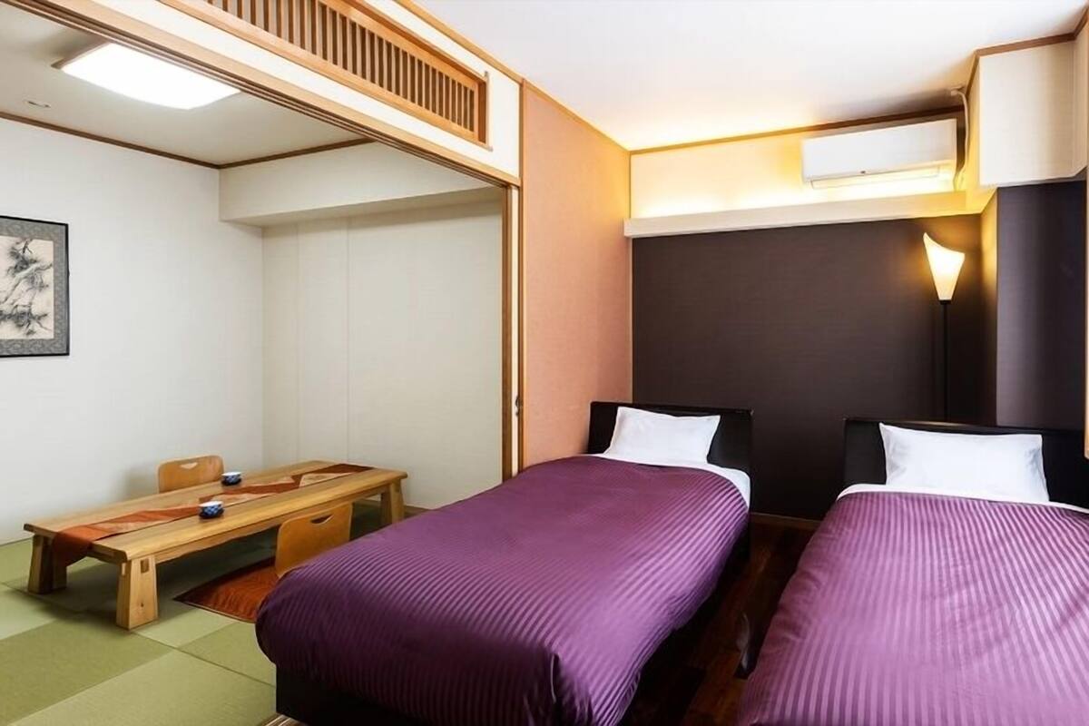 A room with two beds, a desk, a chair, and a window with a view.