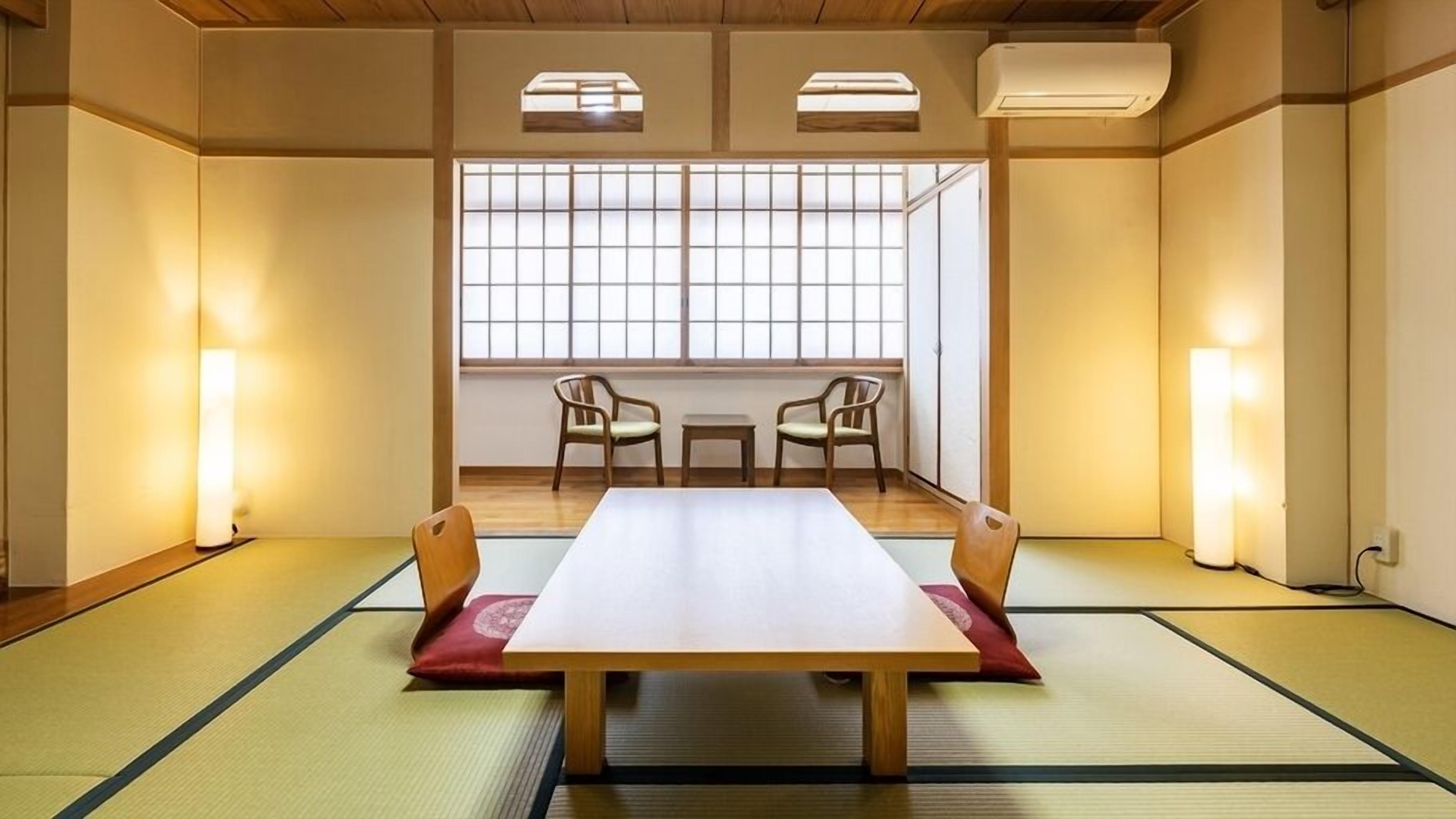 A traditional tatami room with a low table, two chairs, and sliding doors.