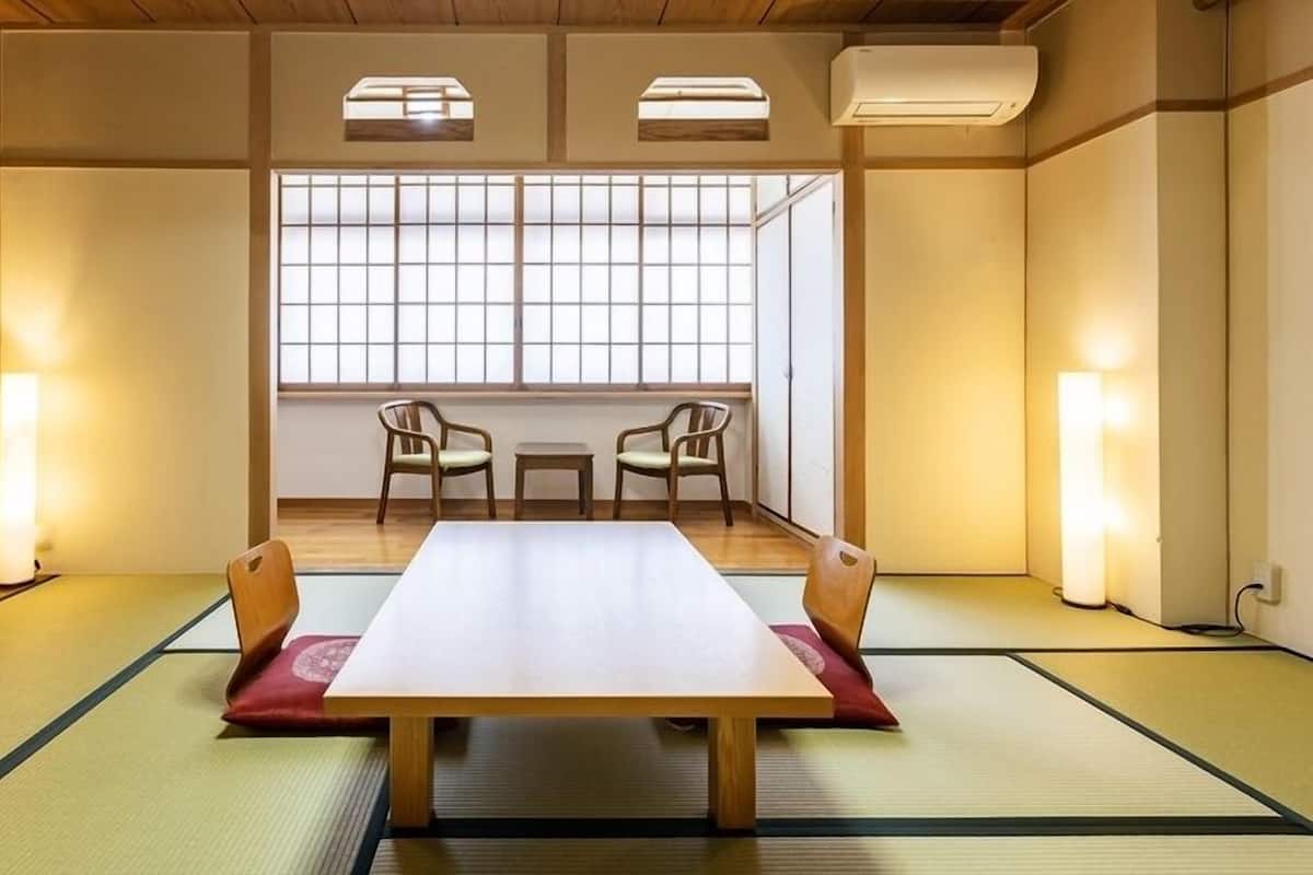 A traditional tatami room with a low table, two chairs, and sliding doors.
