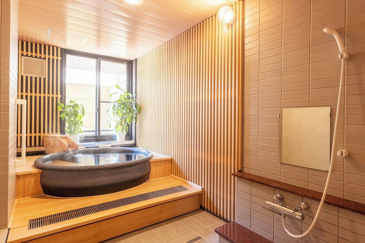 A modern bathroom with a hot tub, a shower, and a window with plants.