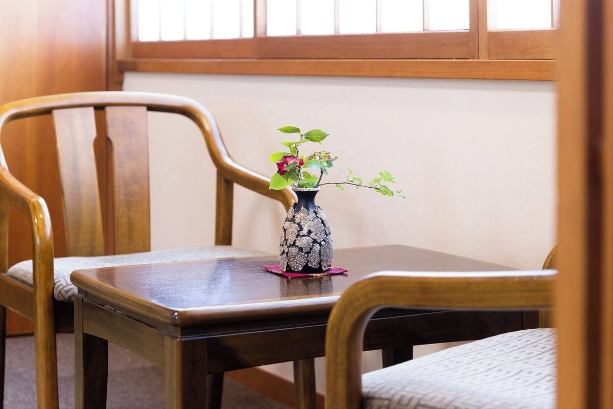 A wooden chair and table with a vase of flowers.