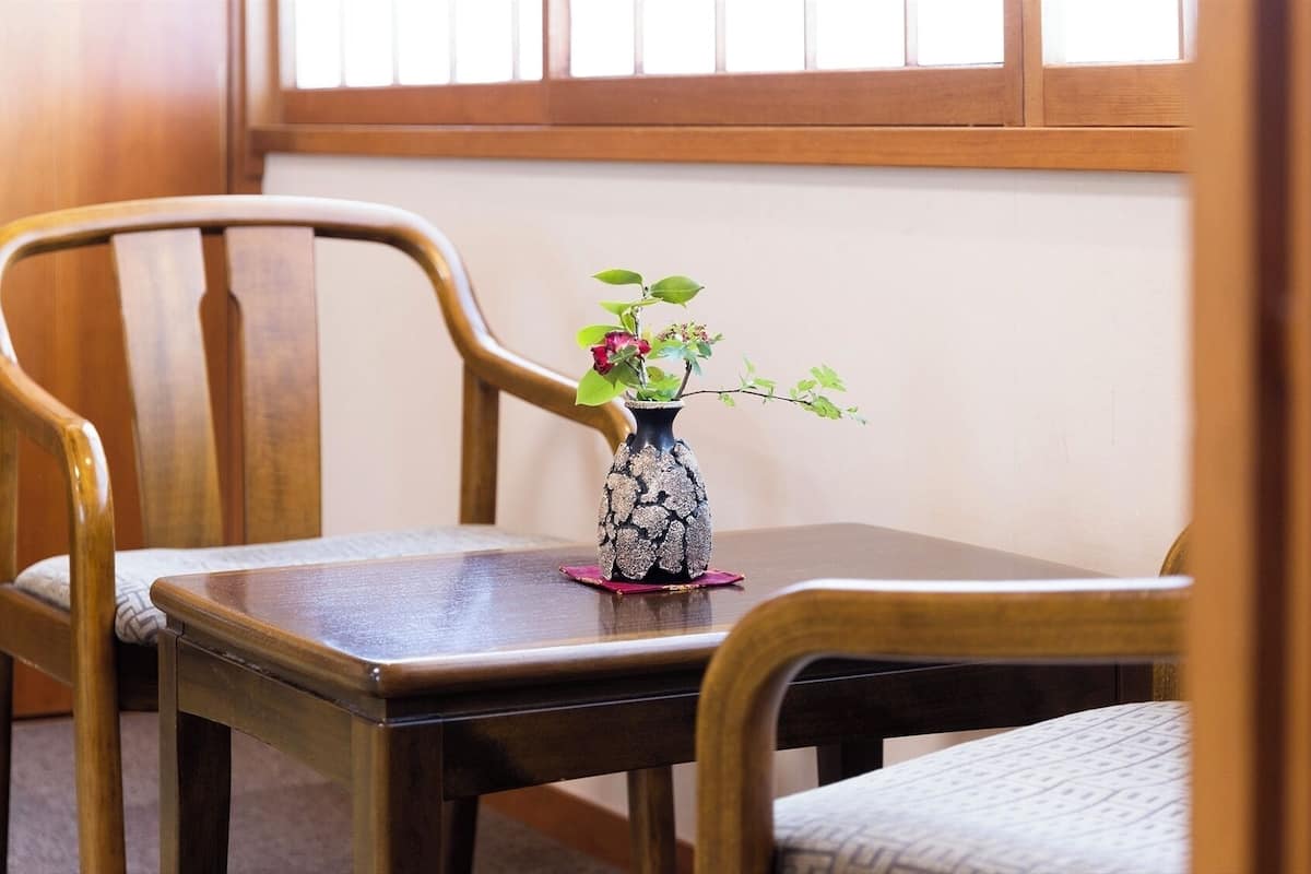 A wooden chair and table with a vase of flowers.
