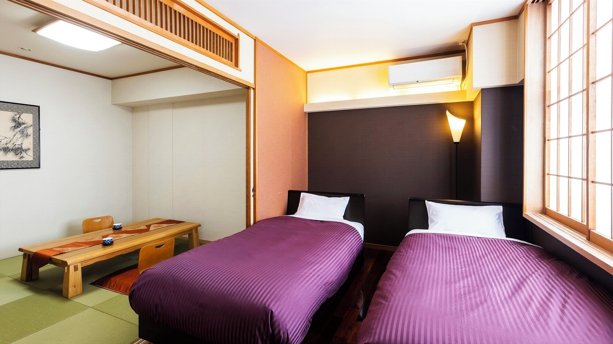 Ett hotellrum med två sängar, ett skrivbord, en stol och ett fönster med utsikt.