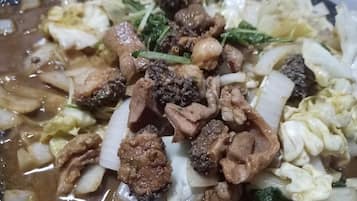 A close-up of a dish with various ingredients, including meat and vegetables in a broth.