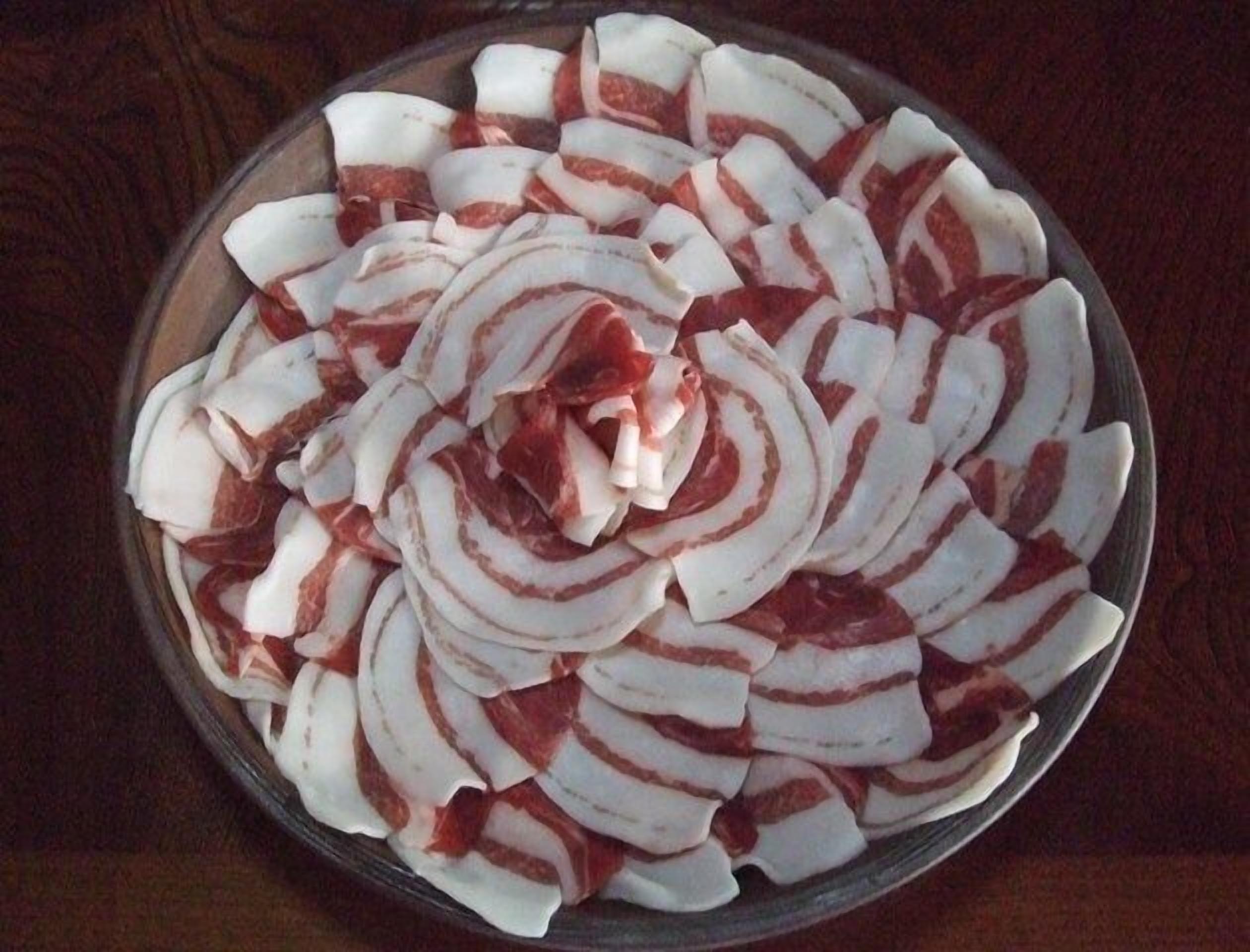 A round glass bowl containing sliced white and red items, possibly food, arranged in a circular pattern.