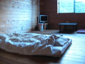 A room with a bed, a television, a small table, and a window.