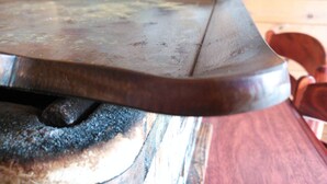 A close-up of a metal surface with a handle, possibly a part of a kitchen appliance, against a wooden background. - Shiozawasanso (Takayama)
