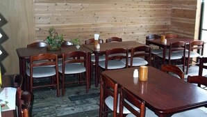 A dining area with wooden walls, multiple tables, and chairs. - Shiozawasanso (Takayama)
