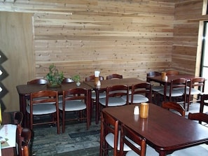 A dining area with wooden walls, multiple tables, and chairs. - Shiozawasanso (Takayama)