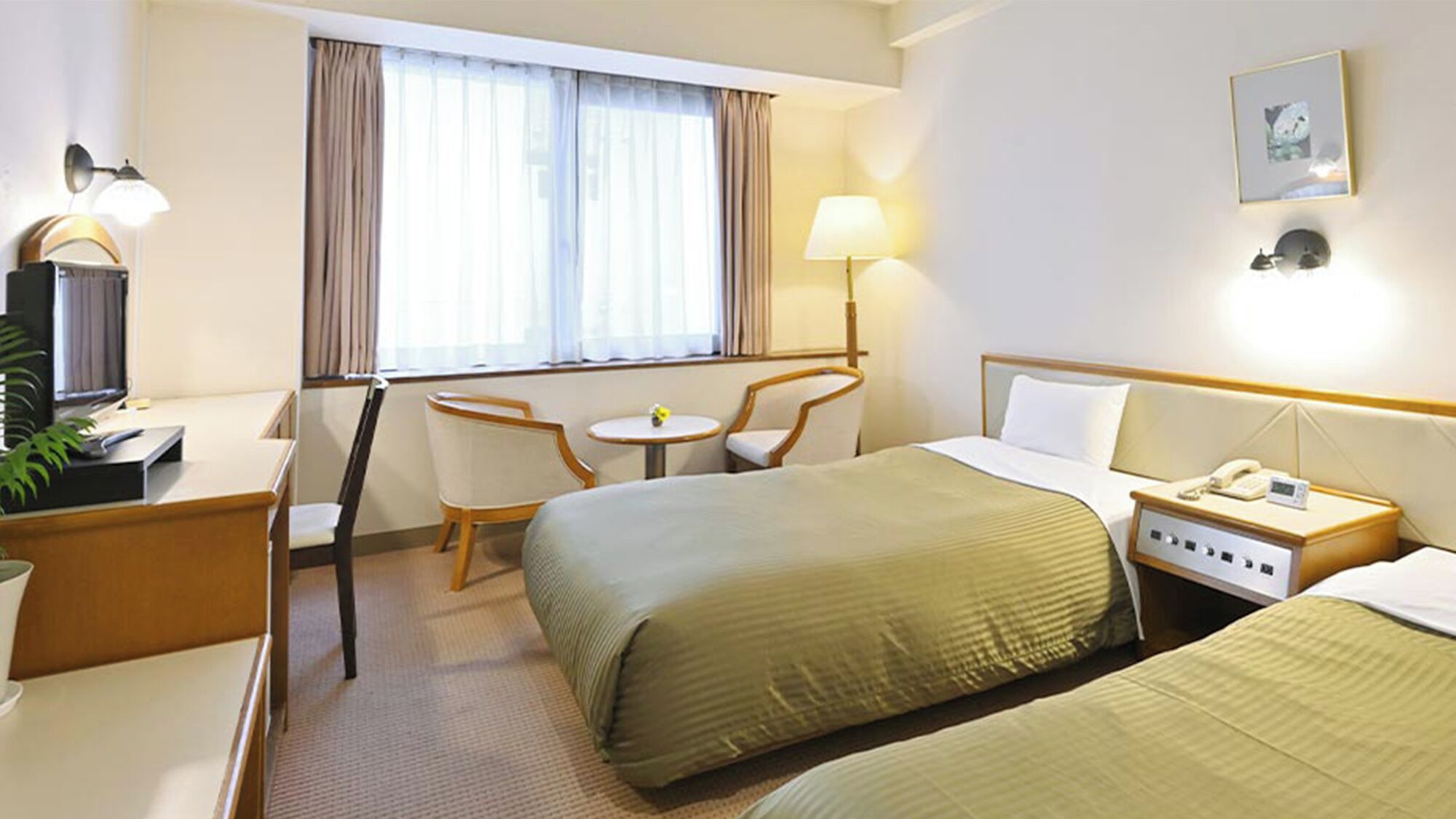 Hotellihuone, jossa on sänky, yöpöytä, lamppu, tuoli, työpöytä, televisio ja ikkuna, jossa on verhot.