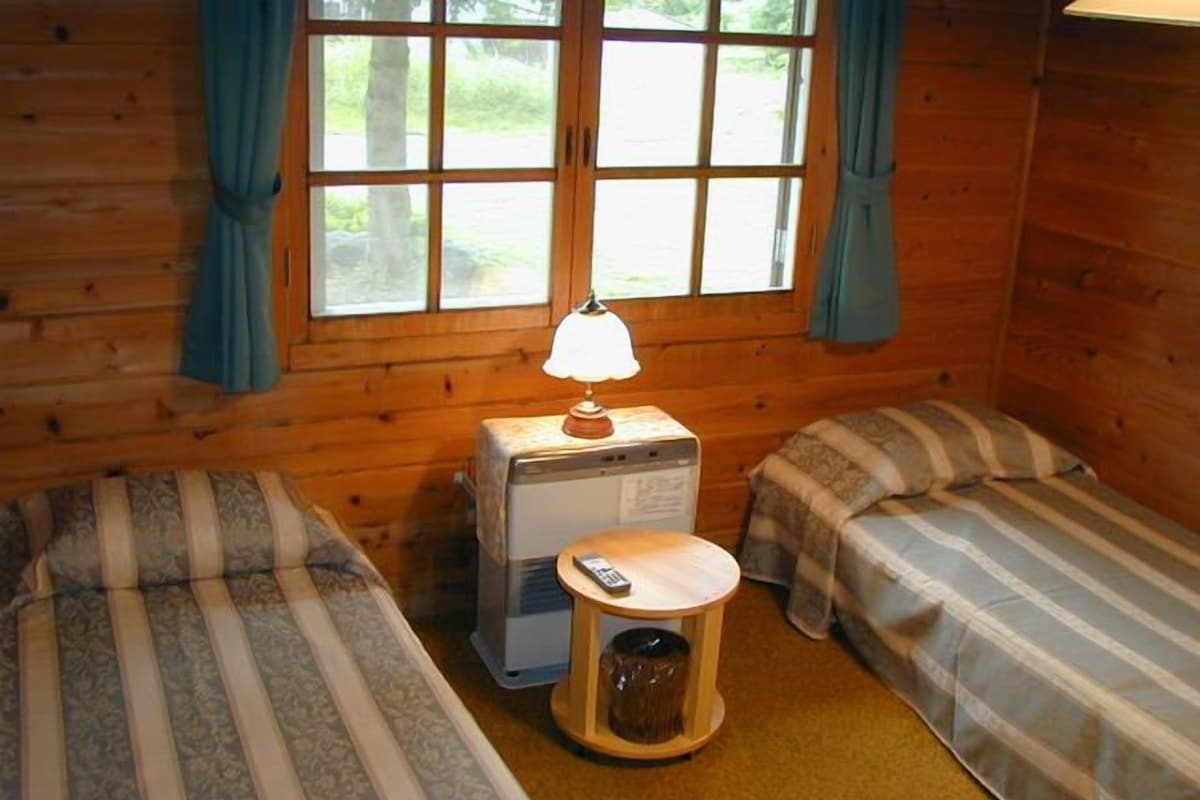 A cabin room with two single beds, a small heater, and a trash bin.