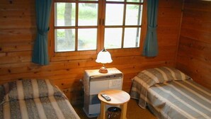 Ein Cabin-Zimmer mit zwei Einzelbetten, einem kleinen Heizgerät und einer Mülltonne.
