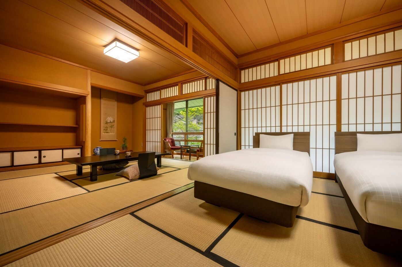 Ett traditionellt japanskt rum med tatamimattor på golvet, ett lågt bord, två sängar och shoji-skärmar.