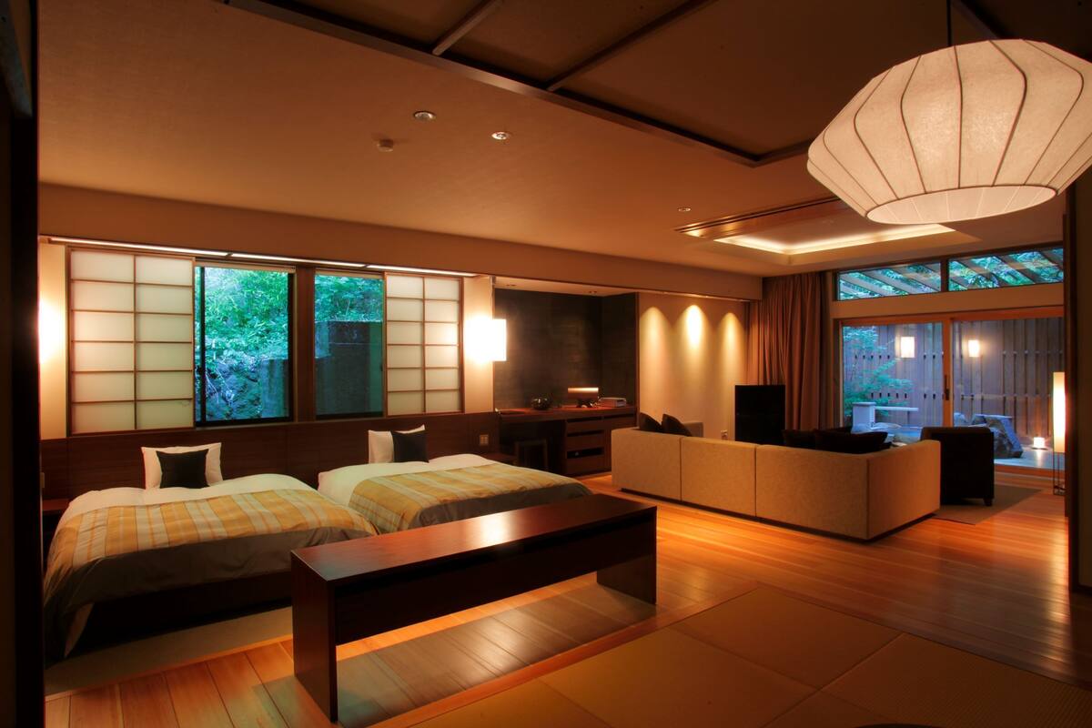 A modern hotel room with a bed, sofa, and a desk area.