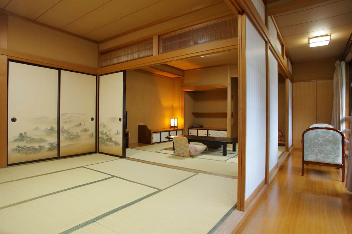 Perinteinen japanilainen huone, jossa on tatamimatto, liukuseinät, matala pöytä ja tuoli.