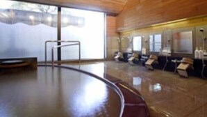 A spacious indoor area with a large circular floor, wooden ceiling, and a row of chairs along the wall. - Kounkan (Shibukawa)