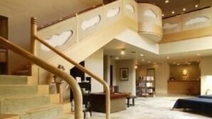 A spacious interior with a curved staircase, a large seating area, and a high ceiling. - Kounkan (Shibukawa)
